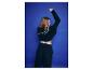 Frau in schwarzem Hoodie und Jogginghose, mit erhobenem Arm, vor blauem Hintergrund.