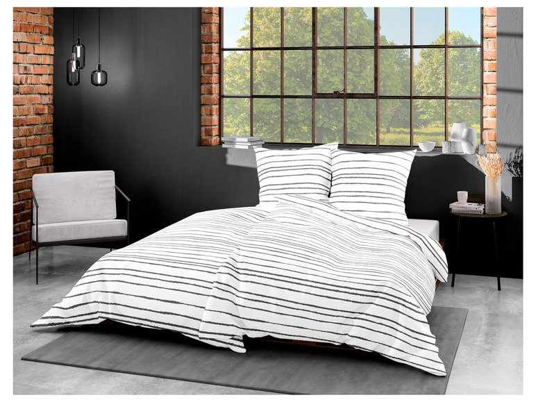 Ein Bett mit gestreiftem weiß und grauem Bettzeug.