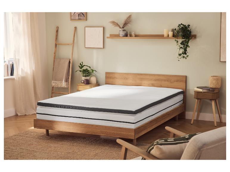 Schlafzimmer mit Holzbett, Matratze und Topper, Nachttischen und Dekorationen.