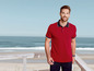 Mann in einem roten Poloshirt mit blauem Rand am Strand.