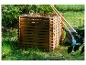 Holzkomposter gefüllt mit Gartenabfällen, mit Rechen und einer Gartentasche daneben.