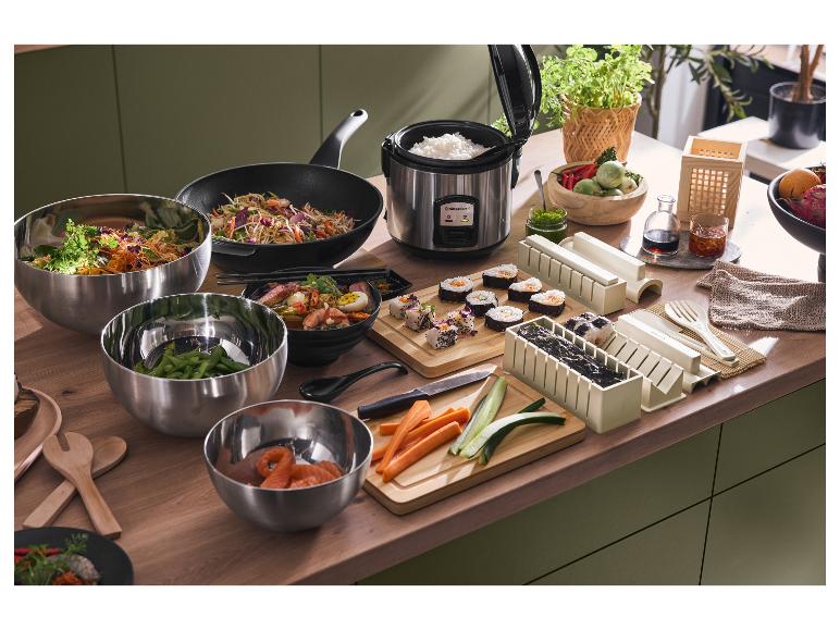 Asiatisches Kochen mit Silvercrest Reiskocher, Wok, Sushi-Formen und Schüsseln auf Holzarbeitsplatte.