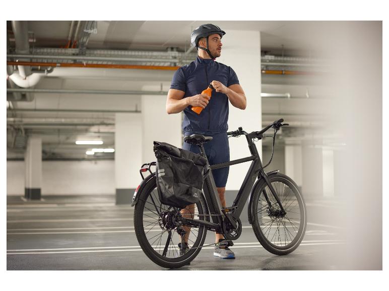Radfahrer mit E-Bike und Ortlieb Tasche auf einem Parkplatz.