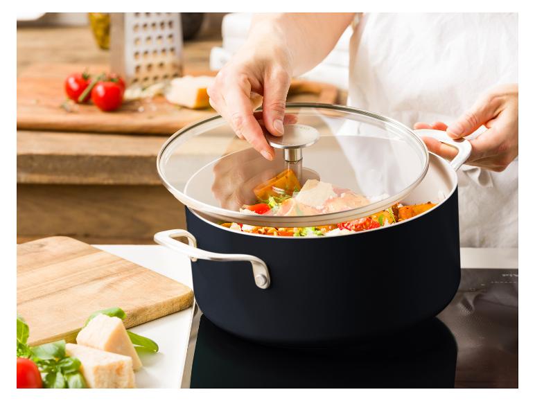 Eine Person hebt den Glasdeckel eines KitchenAid-Topfes voller Gemüse und Käse an.