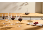 Rotwein in Gläsern und einer Karaffe auf einem Holztisch mit Käse und Trauben.