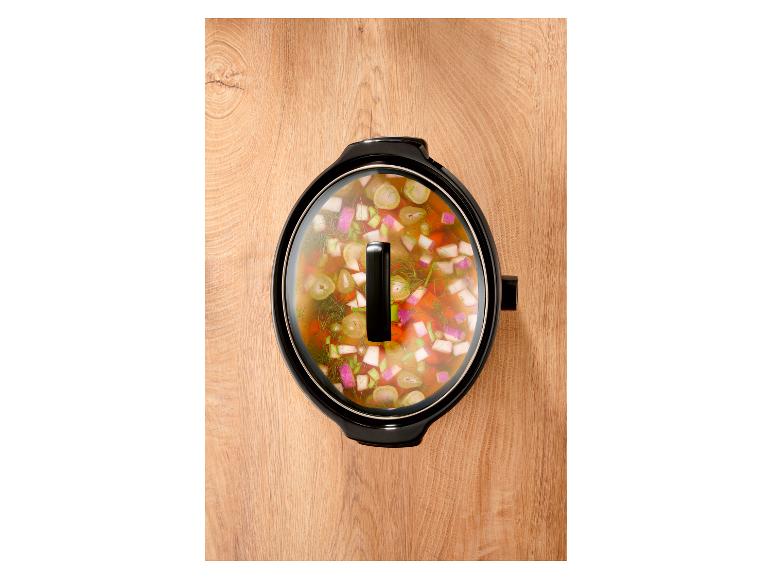 Slow Cooker mit Gemüseeintopf auf einer Holzoberfläche, Draufsicht.