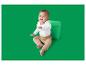 Baby in weißem Langarm-Body und beiger Hose, sitzt neben einem grünen Würfel.