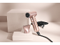 Roségoldener Haartrockner mit Aufsatz und schwarzer Tasche auf neutralem Hintergrund.