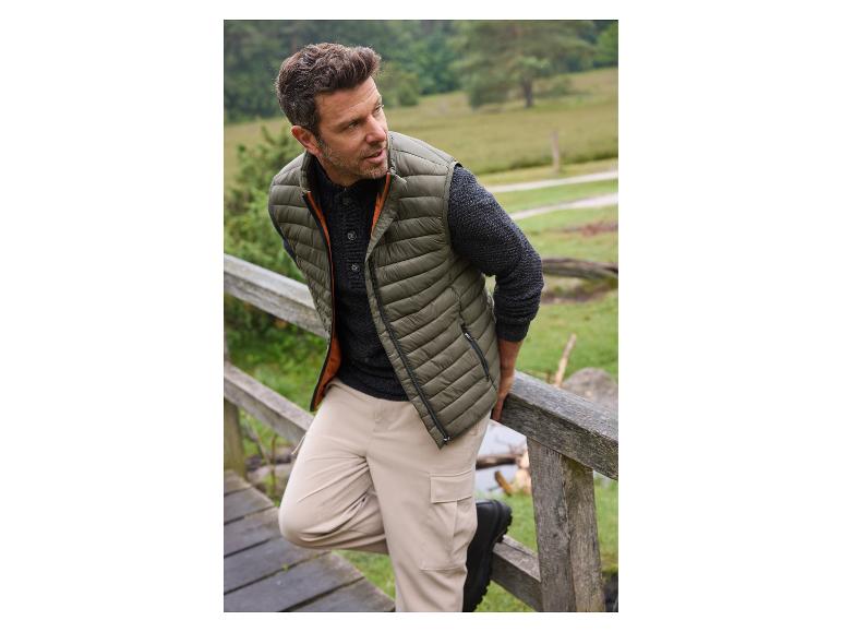 Mann in grüner Daunenweste und beigefarbener Hose.