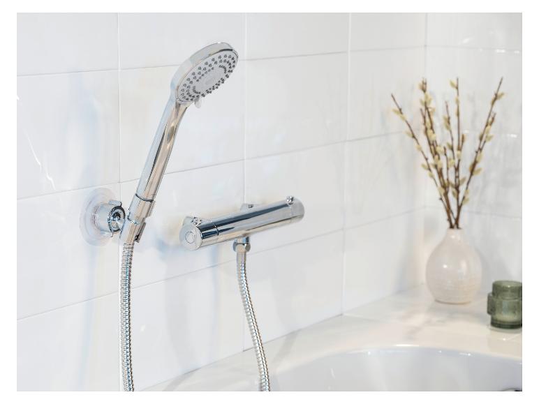 Moderne verchromte Duschgarnitur an einer weißen Fliesenwand montiert.