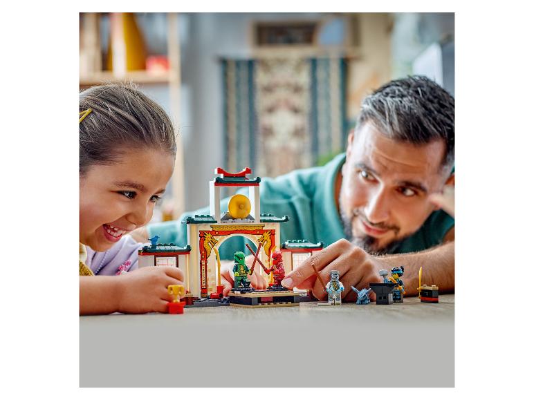 Vater und Tochter spielen mit einem LEGO Ninjago Set auf dem Boden.