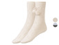 Zwei Paar gestrickte Socken mit Bommel-Verzierung.
