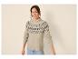 Frau in beigem Fair Isle Pullover und Jeans, lächelt in die Kamera.