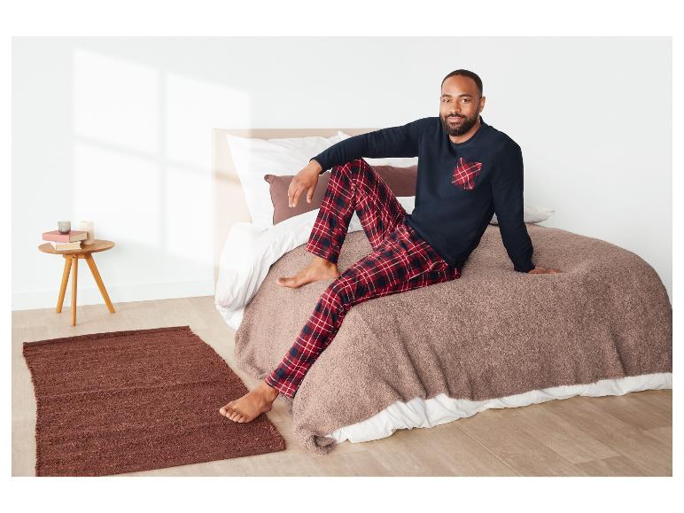 Mann in roter karierter Pyjama auf einem Bett.