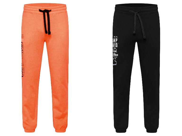Zwei orangefarbene und schwarze Jogginghosen mit gestickten Logos.
