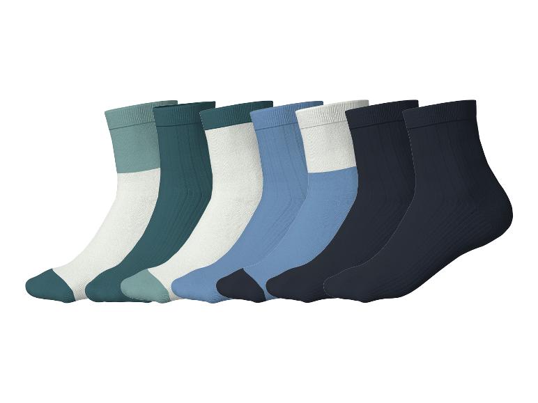 Sieben Paar bunte Socken diagonal auf weißem Hintergrund angeordnet.