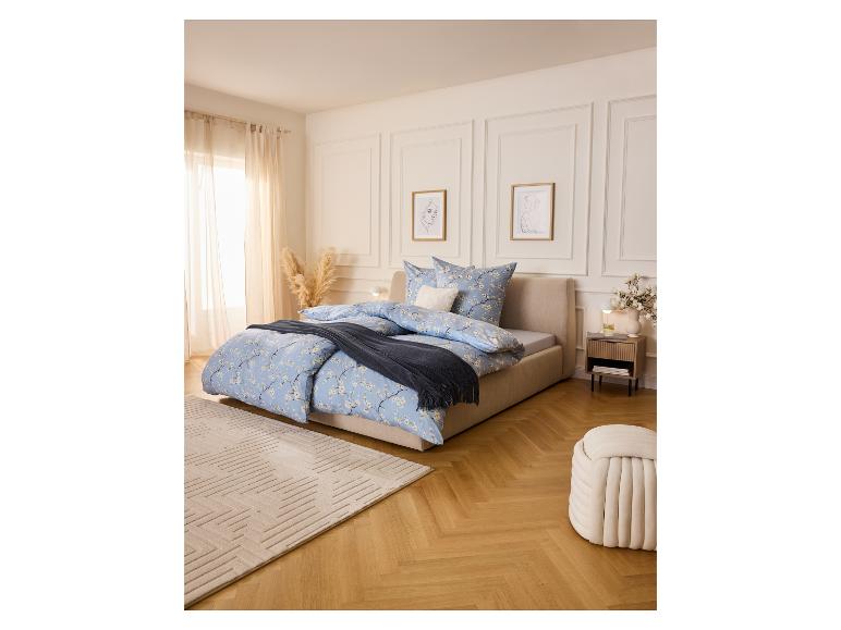 Schlafzimmer mit Bett, LIVARNO® Nachttisch, Teppich und Pouf in hellen Farben.