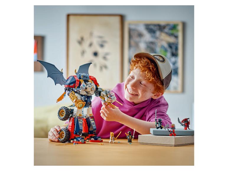 Glücklicher Junge spielt mit einem großen LEGO Ninjago Mech und Minifiguren auf einem Tisch.