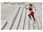 Frau in Sportkleidung läuft die Treppe hinauf.