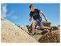 Mann in schwarzem T-Shirt und blauen Shorts läuft auf Felsen.