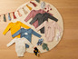 Babykleidung mit langen Ärmeln, darunter ein rosa Body mit Fuchs, ein grauer Body und ein blauer Body mit Bär.