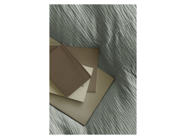 Beige und braune Notizbücher und Blöcke auf grünem Stoff.