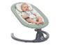 Lächelndes Baby in einer grünen Babywippe mit Meeresmotiv.