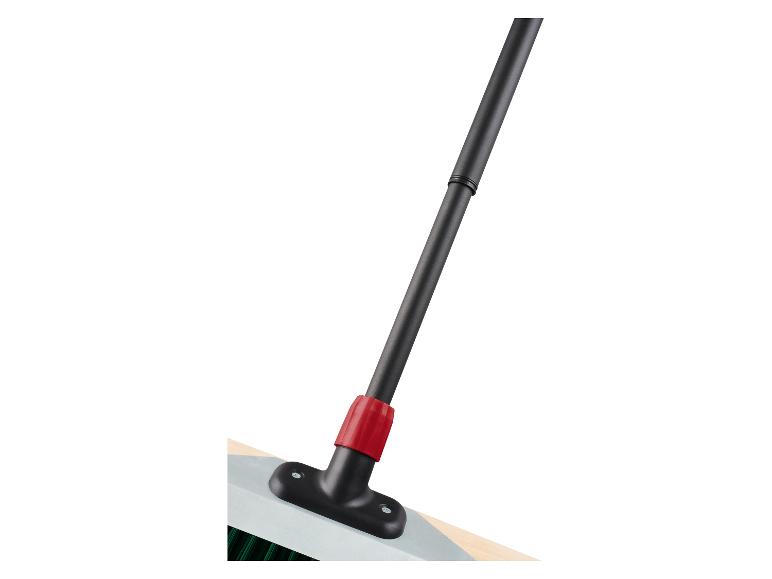Nahaufnahme eines Besens mit schwarzem Stiel und rotem Verbinder, befestigt an einer hellen Basis.