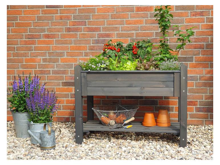Hochbeet aus dunklem Holz mit Tomaten, Salat und Kräutern.
