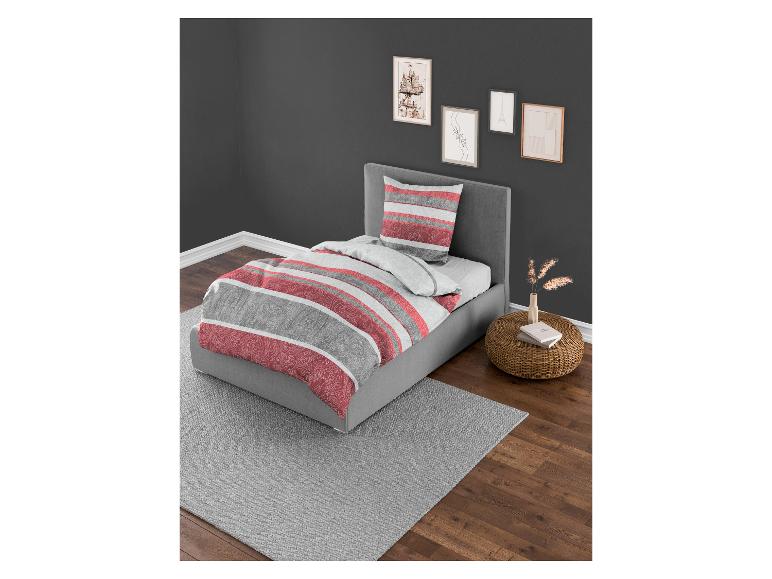 Ein Bett mit roter und grauer gestreifter Bettdecke und passendem Kissen.