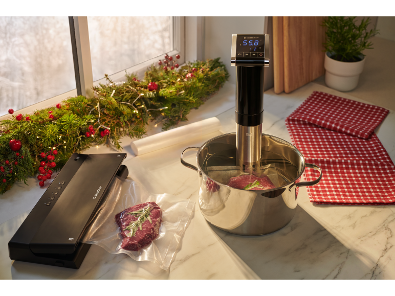 Vakuumierer und Sous-Vide-Gerät mit Fleisch, das in weihnachtlicher Atmosphäre gart.