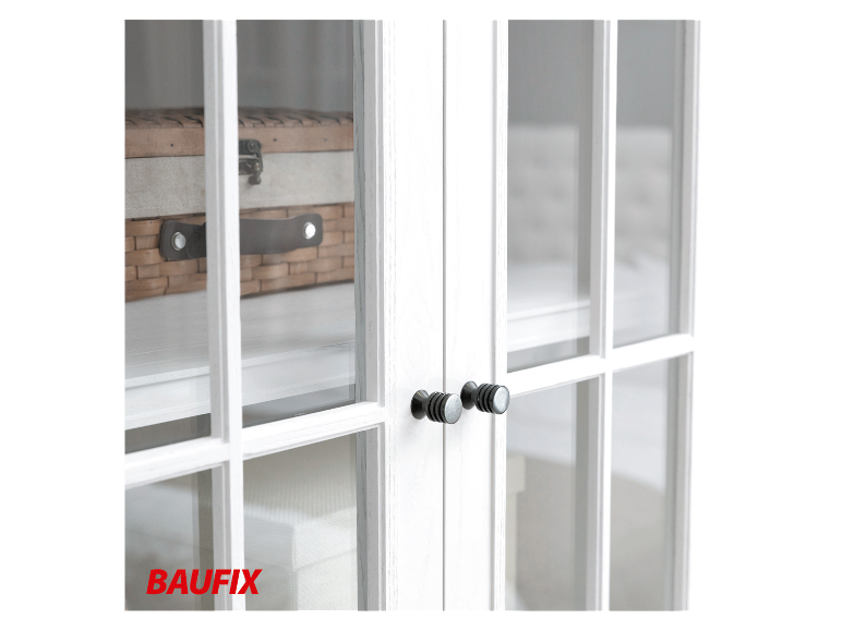 Weiße BAUFix Möbel mit schwarzen Knöpfen und einem Korb aus Weidengeflecht.