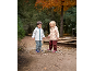 Zwei Kinder in Regenkleidung und Gummistiefeln planschen im Herbst in einer Pfütze.