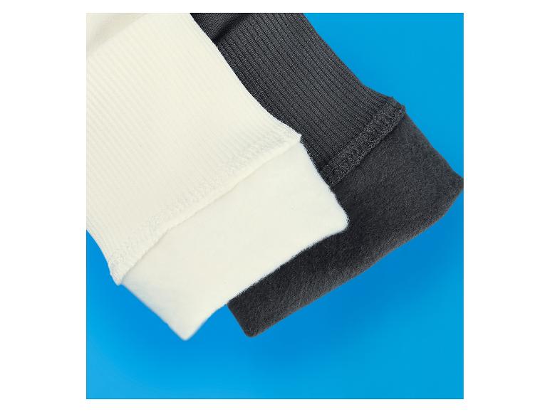 Gerippte Pulloverbündchen in Creme und Dunkelgrau auf blauem Hintergrund.