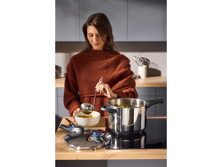 Frau schöpft Suppe aus Edelstahlkochtopf in Schüssel in der Küche.