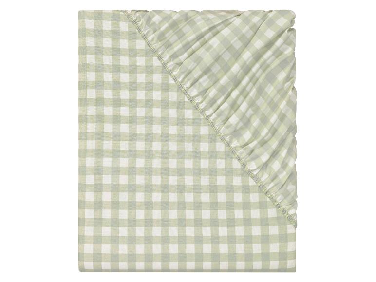 Ein grünes kariertes Spannbettlaken für ein Einzelbett.