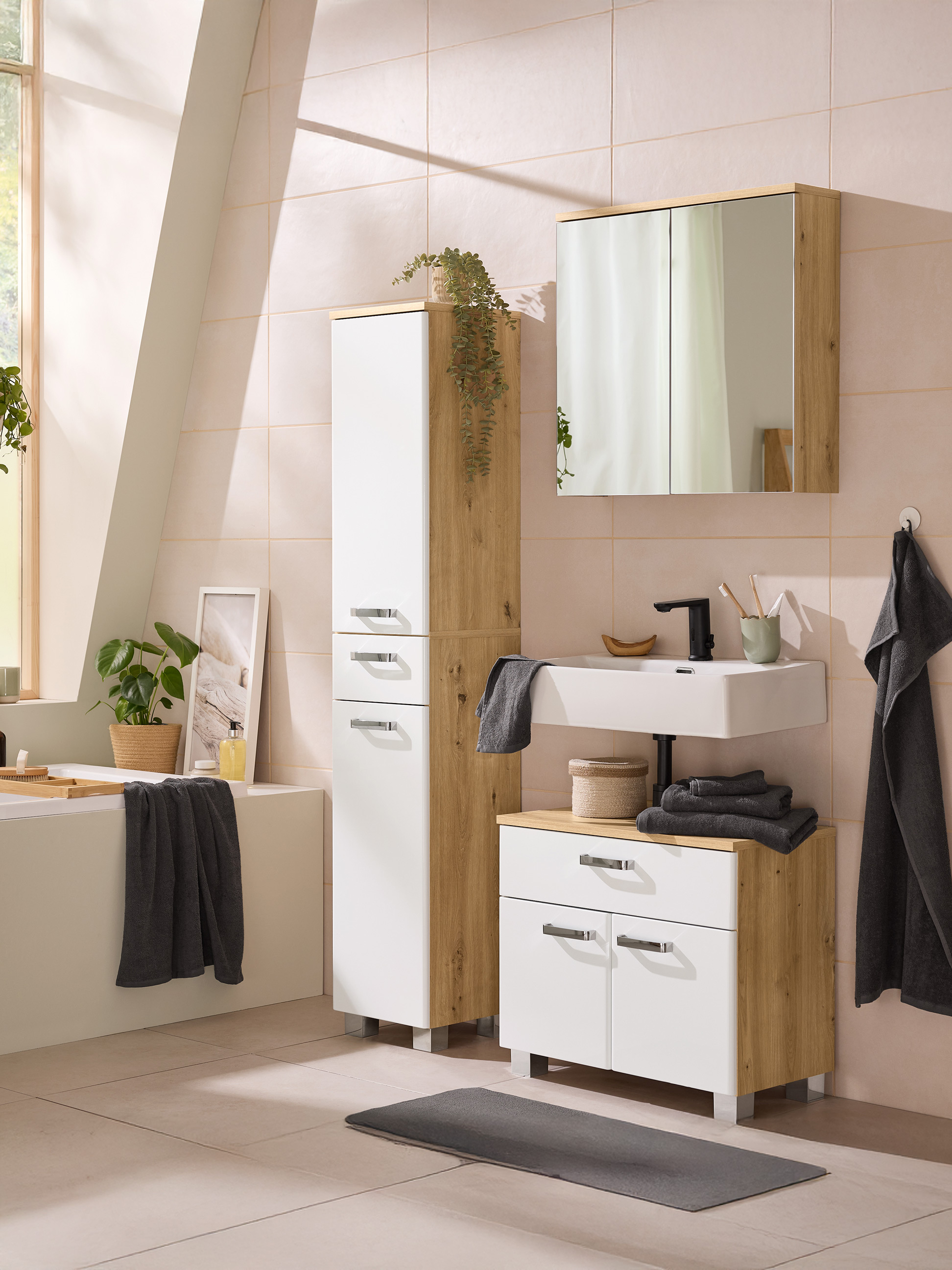Modernes Badezimmer mit hellen Holz- und weißen Möbeln, Waschbecken, Spiegel und grauen Handtüchern.