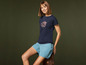 Eine Frau in einem blauen T-Shirt mit Bergdruck und blauen Shorts.