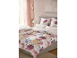 Bett mit floraler Bettwäsche und Kissenbezügen mit gestreiften Details.
