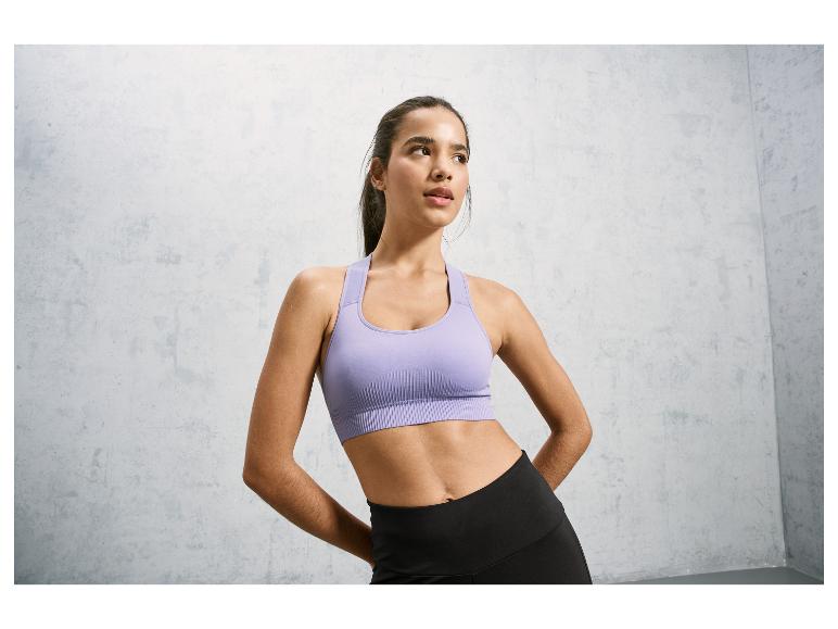 Eine Frau trägt einen lila Sport-BH und schwarze Leggings.