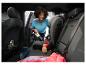 Frau saugt Autoinnenraum mit Handstaubsauger, mit Kindersitz und Gummistiefeln.