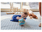 Ein Baby spielt mit einem Spielzeugblock auf einer Spielmatte.