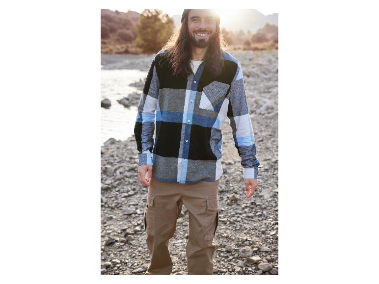 Mann in einem karierten Hemd und einer Khakihose.