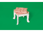 Kinderhocker mit rosa Kissen auf grünem Hintergrund.