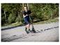 Lächelnder Junge auf einem Roller, in T-Shirt und Shorts, auf einem sonnigen Weg.