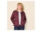 Frau in einer burgunderroten Steppjacke, weißem T-Shirt und dunklen Jeans, blickt nach links.