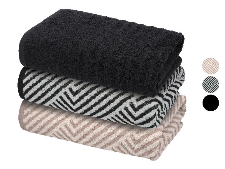 Stapel aus drei gefalteten Handtüchern: schwarz, schwarz-weiß gemustert und beige gemustert.