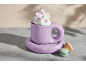 Lila Tasse mit Schlagsahne und Marshmallows, mit zwei Macarons daneben.