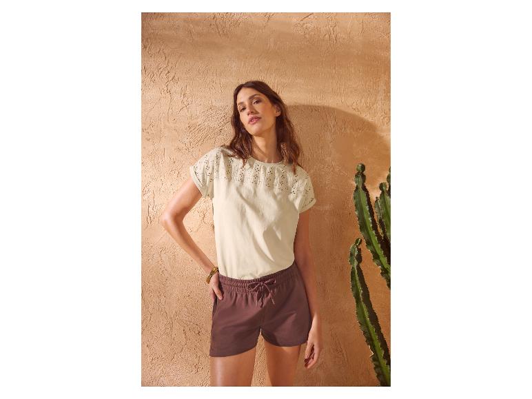 Frau in besticktem Kurzarm-T-Shirt und braunen Shorts mit Kordelzug.