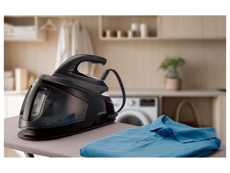 Dampfbügelstation auf einem Bügelbrett mit einem gefalteten blauen Hemd.